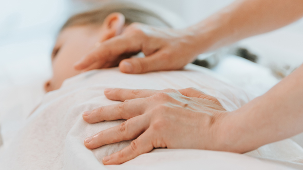 A close-up of a person receiving a soothing massage, with gentle hands on their back, promoting relaxation and comfort.