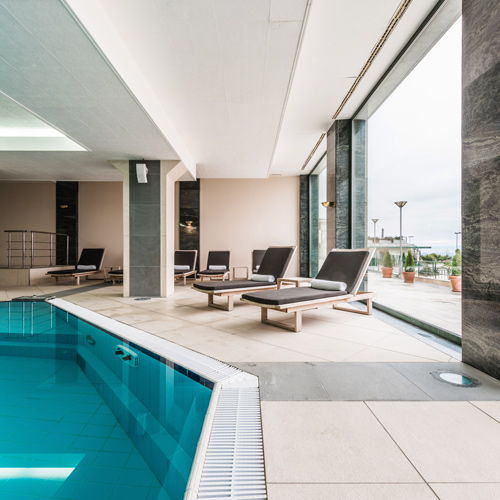 indoor swimming pool area with lounge chairs and large windows offering natural light and a serene atmosphere