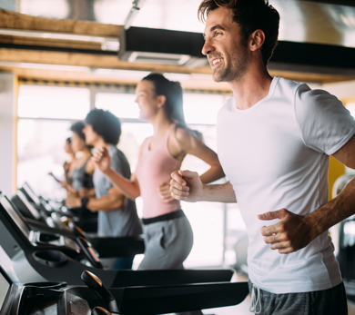 A group of people running on treadmills in a gym, focused on their workout and fitness.