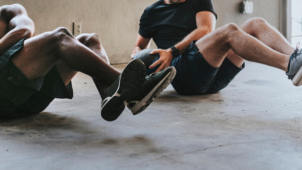 Two people performing an exercise on the floor, focusing on core strength and fitness.