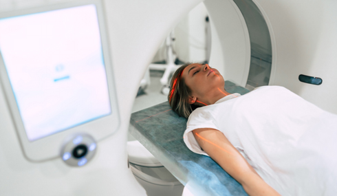 A woman lying on a table inside a medical imaging machine, appearing calm and relaxed during a CT scan procedure.